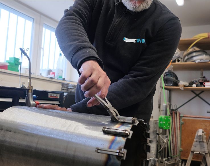 Person schneidet mit einer elektrischen Säge ein Metallrohr.